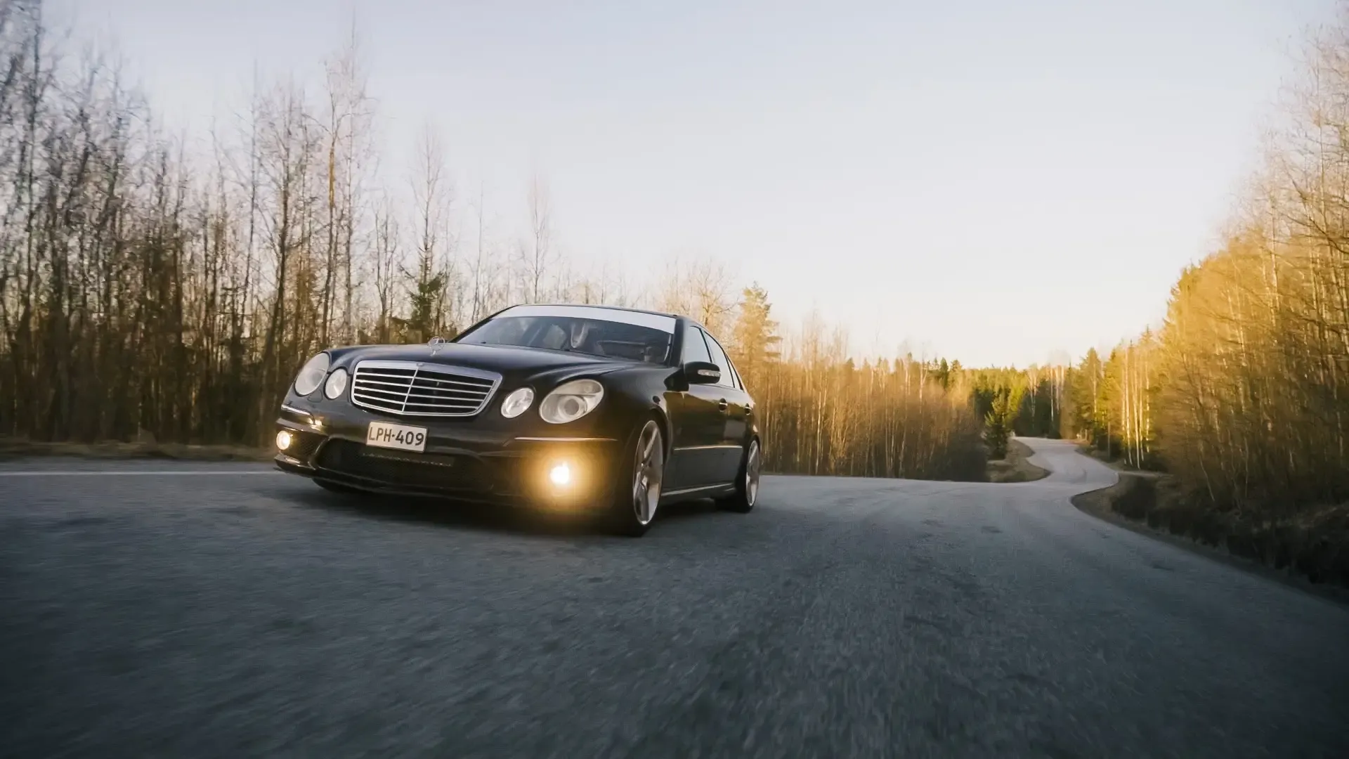 Musta Mercedes liikkeessä ilta-auringossa